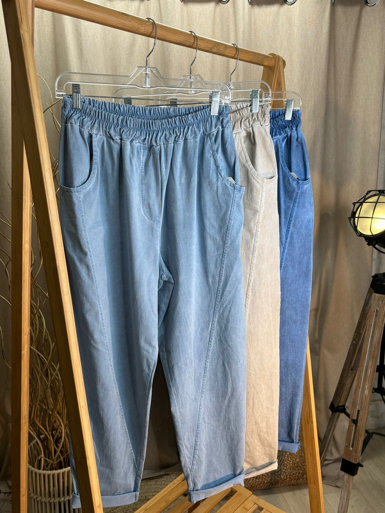 rail of acid wash relaxed magic trousers in light denim, stone and mid denim